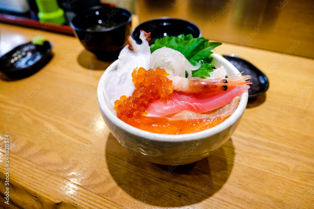 Sashimi served fresh rice bowl on top salmon,tuna, salmon eggs , slice squid and small shrimp, close up sashimi seafood in Japanese style with miso soup and wasabi in Japanese restaurant. Sashimi served fresh rice bowl on top salmon,tuna, salmon eggs , slice squid and small shrimp, close up sashimi seafood in Japanese style with miso soup and wasabi in Japanese restaurant.
