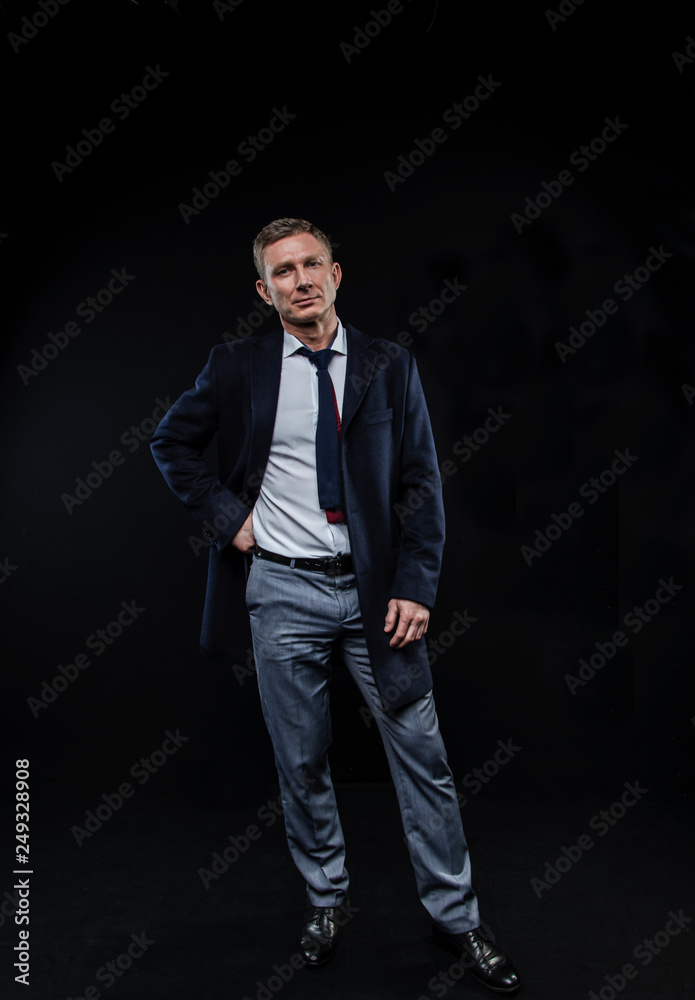 elegant fashionable man in a shirt and coat on standing on a black background elegant fashionable man in a shirt and coat on standing on a black background