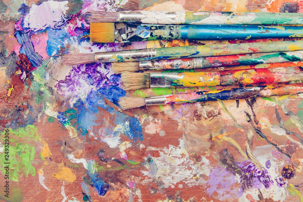 Set of paintbrushes on messy colorful wooden table, grungy background