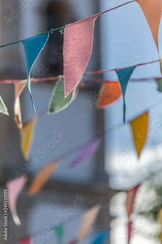 View of traditional decoration of religious festivals on the villages, with colored triangles of paper hanging in threads, church tower on background