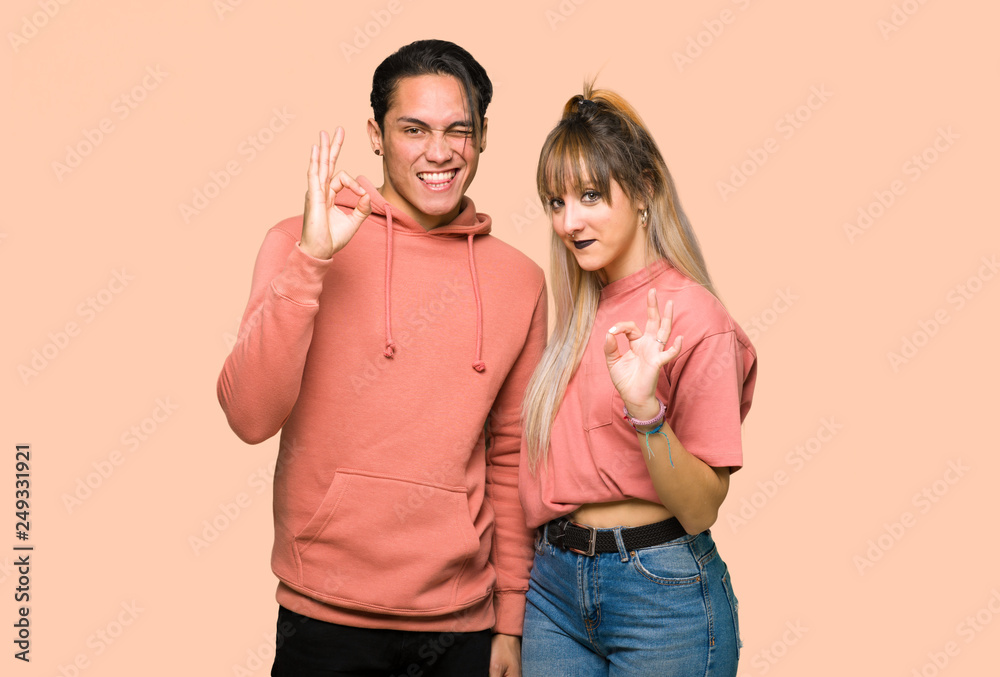 Young couple showing an ok sign with fingers over pink background Young couple showing an ok sign with fingers over pink background