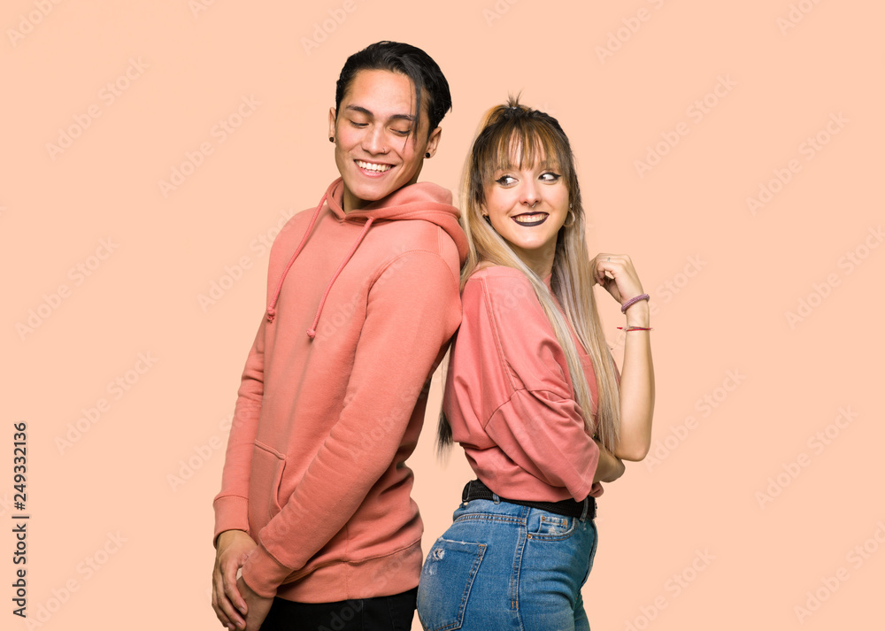 Young couple looking over the shoulder with a smile over pink background Young couple looking over the shoulder with a smile over pink background