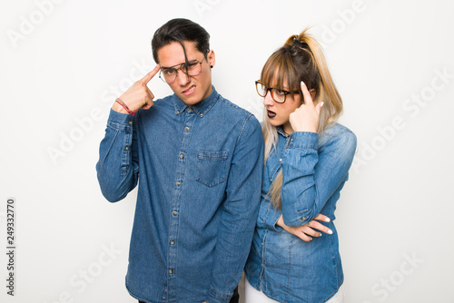 Young couple with glasses making the gesture of madness putting finger on the head