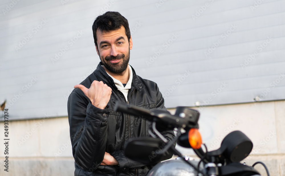 Young man on a motorbike pointing to the lateral Young man on a motorbike pointing to the lateral