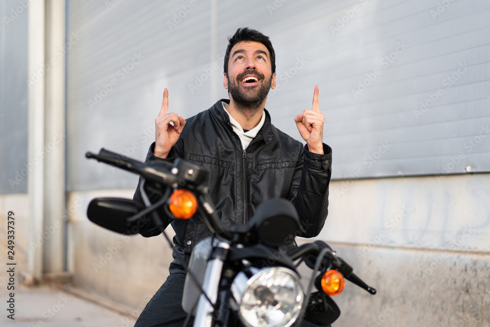 Naklejka premium Young man on a motorbike pointing up