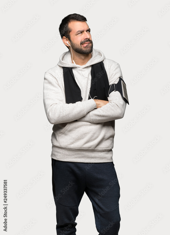 Sport man with confuse face expression while bites lip over isolated grey background Sport man with confuse face expression while bites lip over isolated grey background