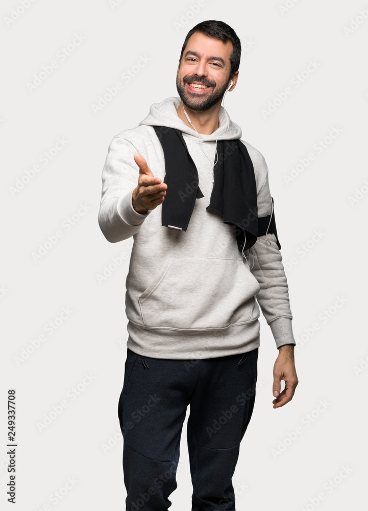 Sport man shaking hands for closing a good deal over isolated grey background Sport man shaking hands for closing a good deal over isolated grey background