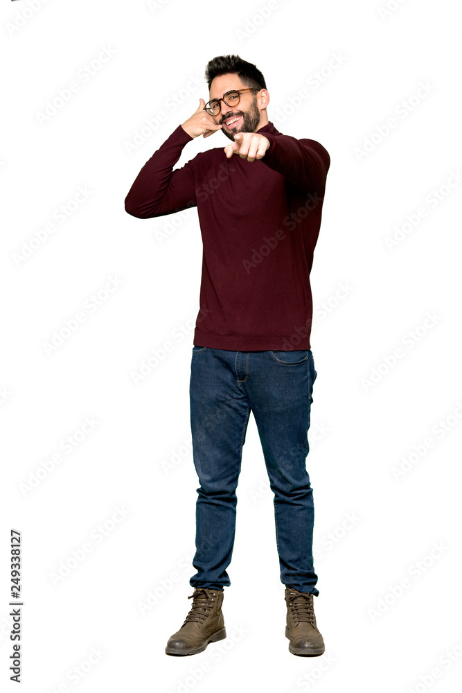 Full-length shot of Handsome man with glasses making phone gesture and pointing front on isolated white background Full-length shot of Handsome man with glasses making phone gesture and pointing front on isolated white background