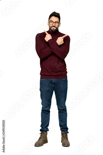 Full-length shot of Handsome man with glasses pointing to the laterals having doubts on isolated white background
