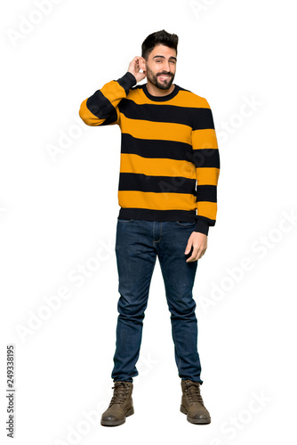 Full-length shot of Handsome man with striped sweater having doubts on isolated white background