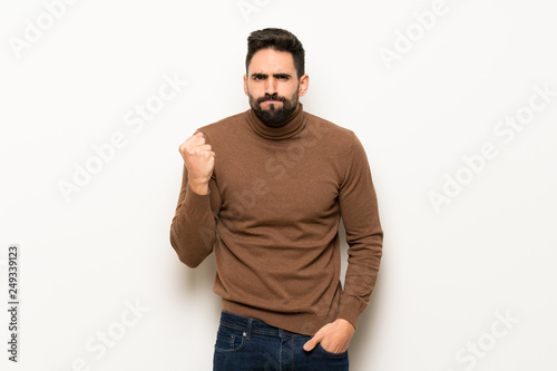 Handsome man over white wall with angry gesture
