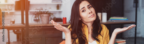Fotografie Confused brunette woman in yellow shirt standing with hands up