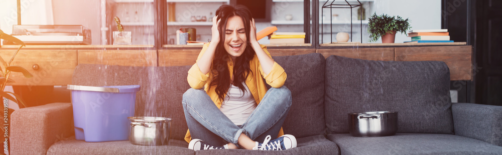 Obraz premium Stressed woman sitting on sofa and screaming with closed eyes