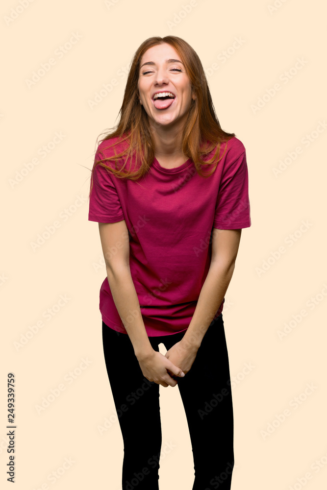 Obraz premium Young redhead girl showing tongue at the camera having funny look on isolated yellow background