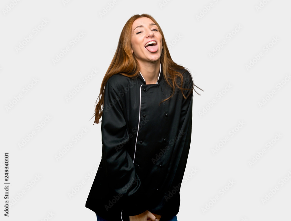 Young redhead chef woman showing tongue at the camera having funny look on isolated grey background Young redhead chef woman showing tongue at the camera having funny look on isolated grey background