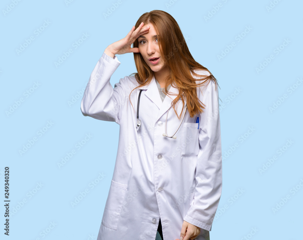 Redhead doctor woman has just realized something and has intending the solution on isolated blue background Redhead doctor woman has just realized something and has intending the solution on isolated blue background