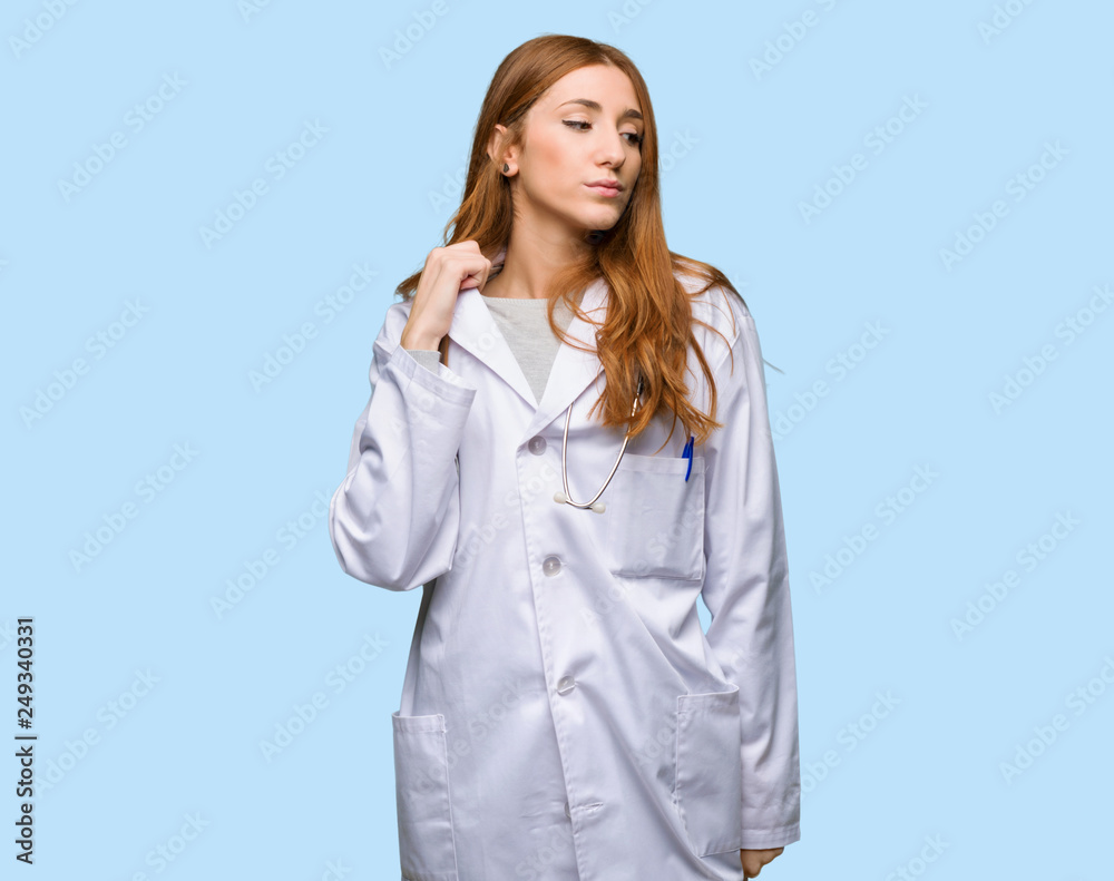 Redhead doctor woman with tired and sick expression on isolated blue background Redhead doctor woman with tired and sick expression on isolated blue background
