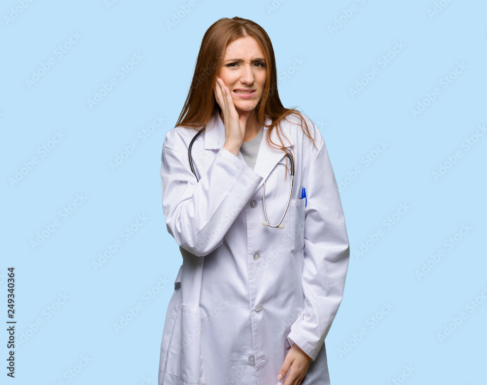 Redhead doctor woman with toothache on isolated blue background Redhead doctor woman with toothache on isolated blue background