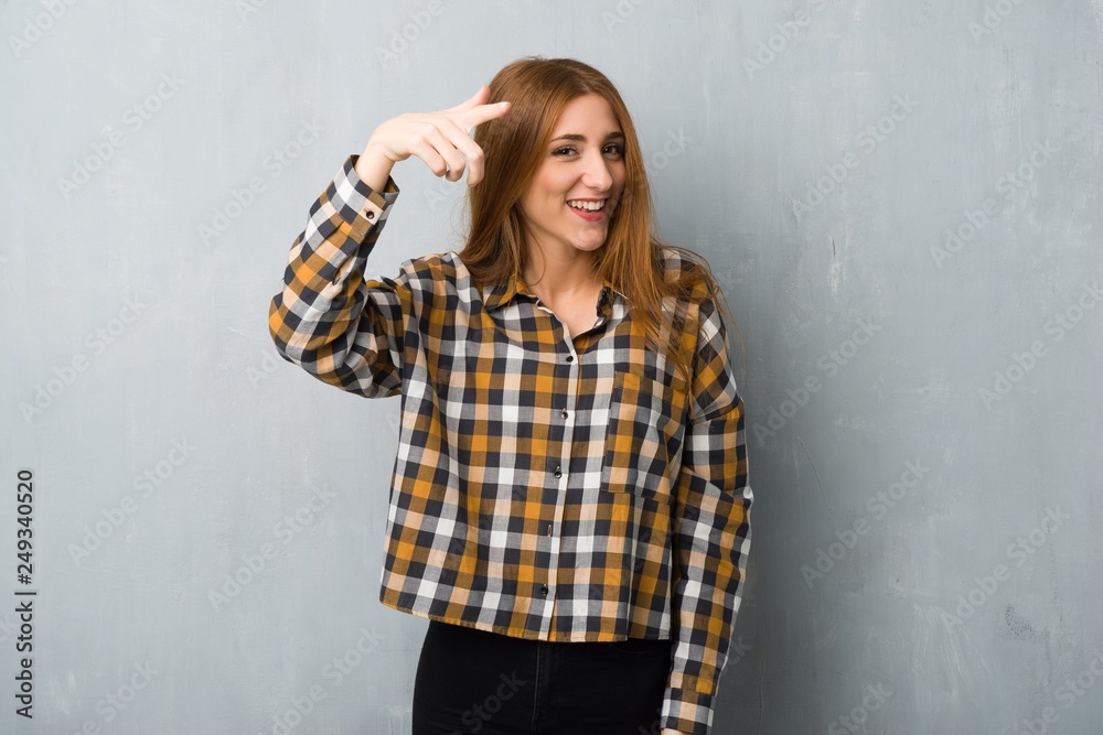 Young redhead girl over grunge wall frustrated by a bad situation and pointing to the front Young redhead girl over grunge wall frustrated by a bad situation and pointing to the front