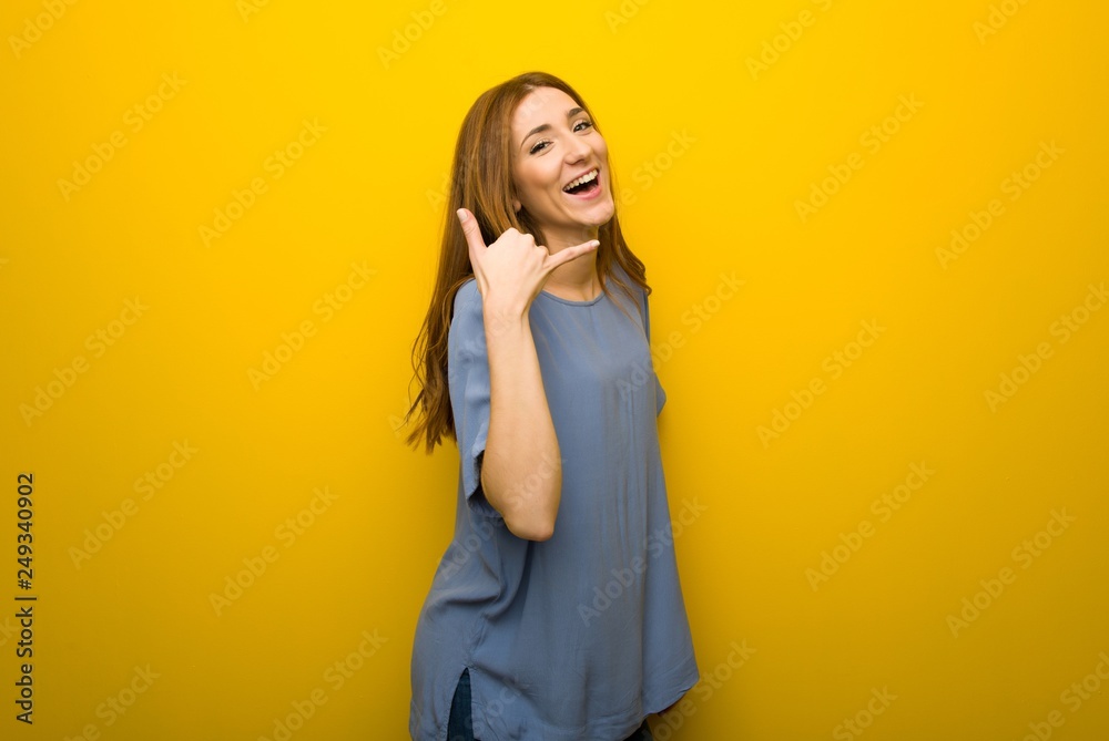 Young redhead girl over yellow wall background making phone gesture. Call me back sign Young redhead girl over yellow wall background making phone gesture. Call me back sign