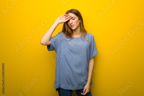 Young redhead girl over yellow wall background with tired and sick expression © luismolinero