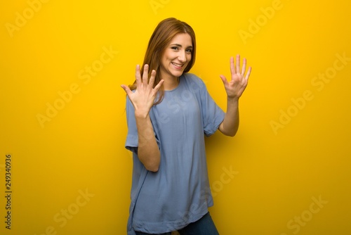 Young redhead girl over yellow wall background counting ten with fingers