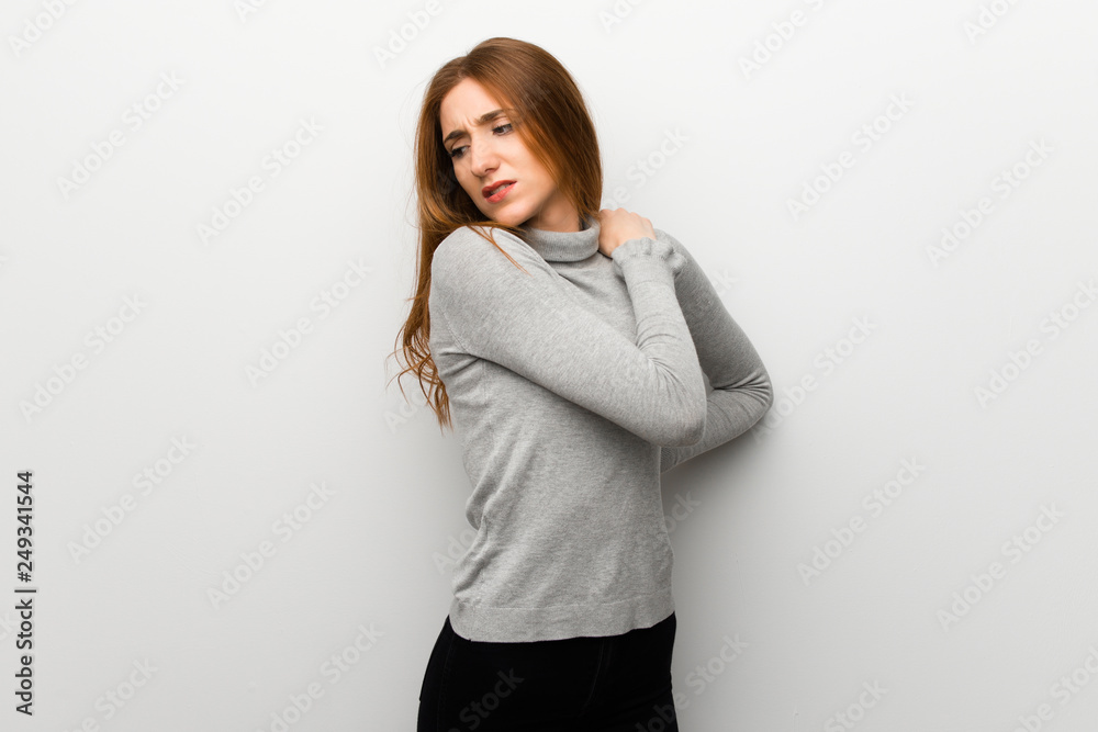 Redhead girl over white wall suffering from pain in shoulder for having made an effort Redhead girl over white wall suffering from pain in shoulder for having made an effort