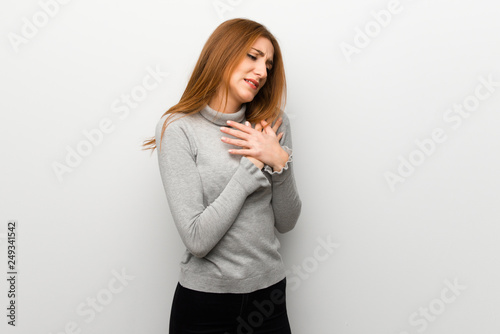 Redhead girl over white wall having a pain in the heart © luismolinero