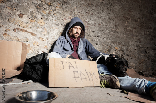 Clochard with dog and cardboard sign on the street photo