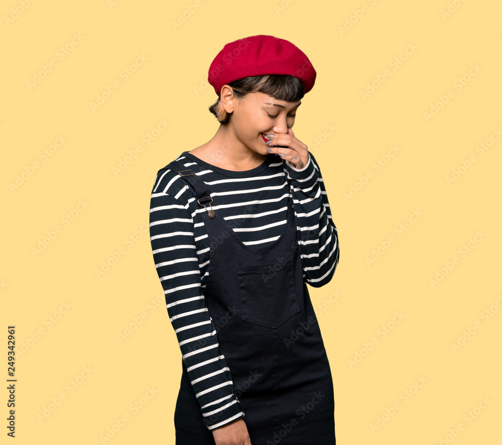 Young woman with beret Happy and smiling over yellow background Young woman with beret Happy and smiling over yellow background