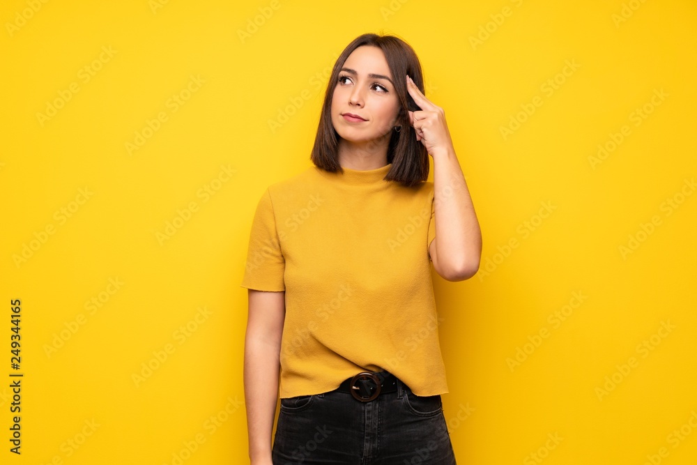 Young woman over yellow wall with problems making suicide gesture Young woman over yellow wall with problems making suicide gesture