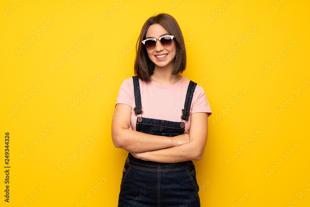 Young woman over yellow wall with glasses and happy Young woman over yellow wall with glasses and happy