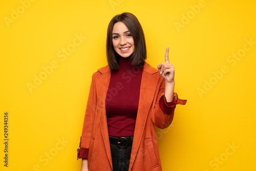 Young woman with coat showing and lifting a finger in sign of the best © luismolinero