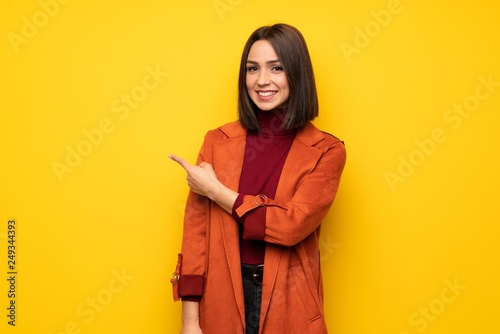 Young woman with coat pointing to the side to present a product © luismolinero