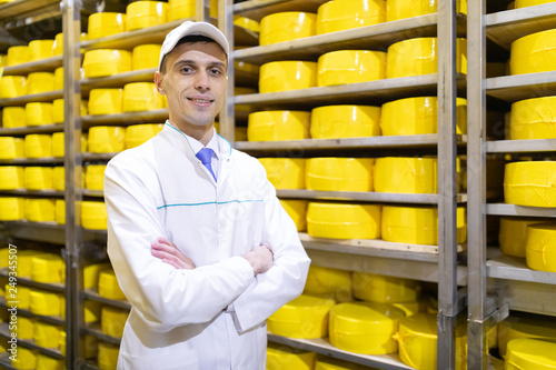 man stands on the background of racks of cheese at the dairy plant