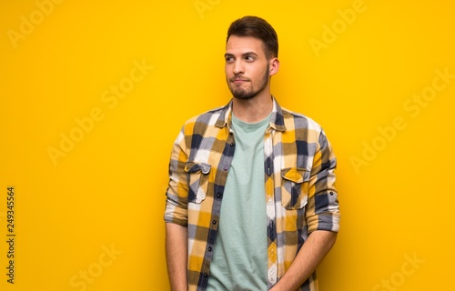 Wallpaper Mural Handsome man over yellow wall with confuse face expression while bites lip Torontodigital.ca