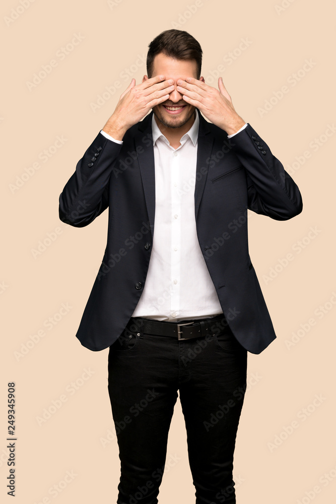 Handsome business man covering eyes by hands. Surprised to see what is ahead over ocher background Handsome business man covering eyes by hands. Surprised to see what is ahead over ocher background