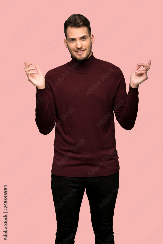 Man with turtleneck sweater having doubts while raising hands over pink background Man with turtleneck sweater having doubts while raising hands over pink background
