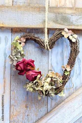 A heart shaped dried flower wreath on a barn blue wall  wall