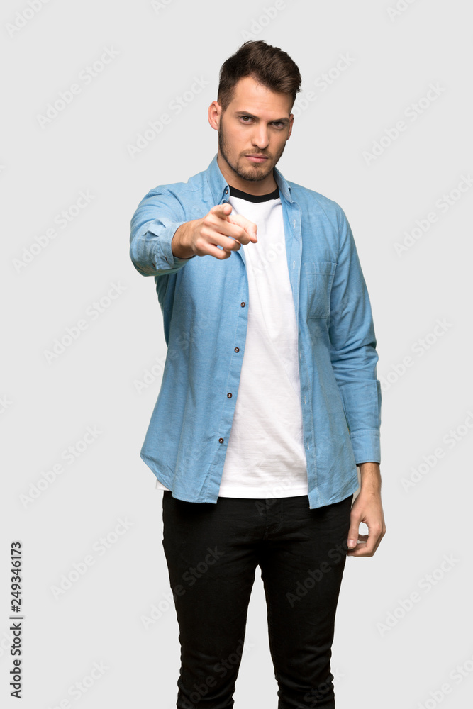 Handsome man frustrated and pointing to the front over grey background Handsome man frustrated and pointing to the front over grey background
