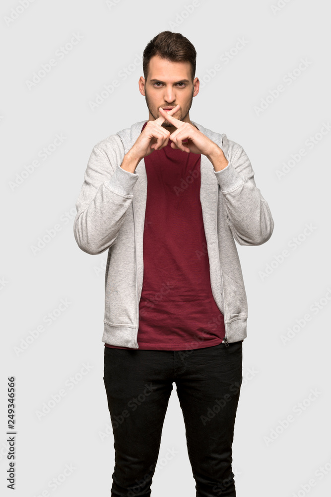 Man with sweatshirt showing a sign of silence gesture over grey background Man with sweatshirt showing a sign of silence gesture over grey background