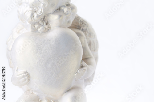 Cherub statue isolated on white background. Angel holds the heart. Love