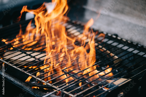 Fotografija burning firewood with flame through bbq grill grates