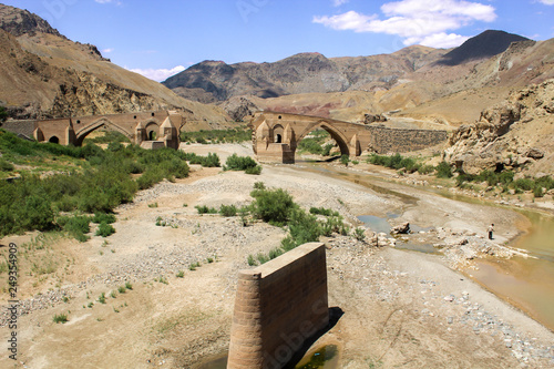 Kiz bridge destroy in Iran by the communist in Tabriz at the dokhtar river with mountains and a iranian guy walking photo