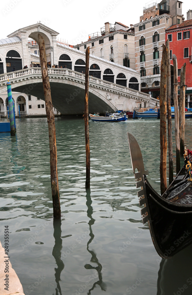 ancient Rialto bridge and a gondola in the water in Venice