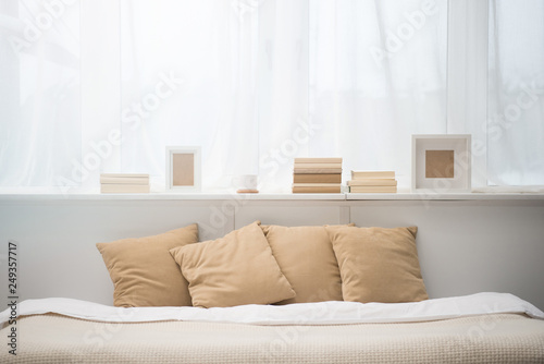 bedroom with brown pillows on bed, books, coffee cup and photo frames