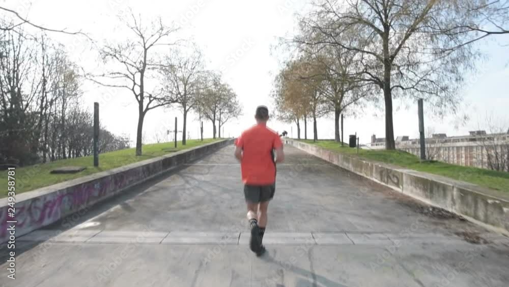 back view young man running uphill outdoor in the city - exercise, challenging, sport concept back view young man running uphill outdoor in the city - exercise, challenging, sport concept