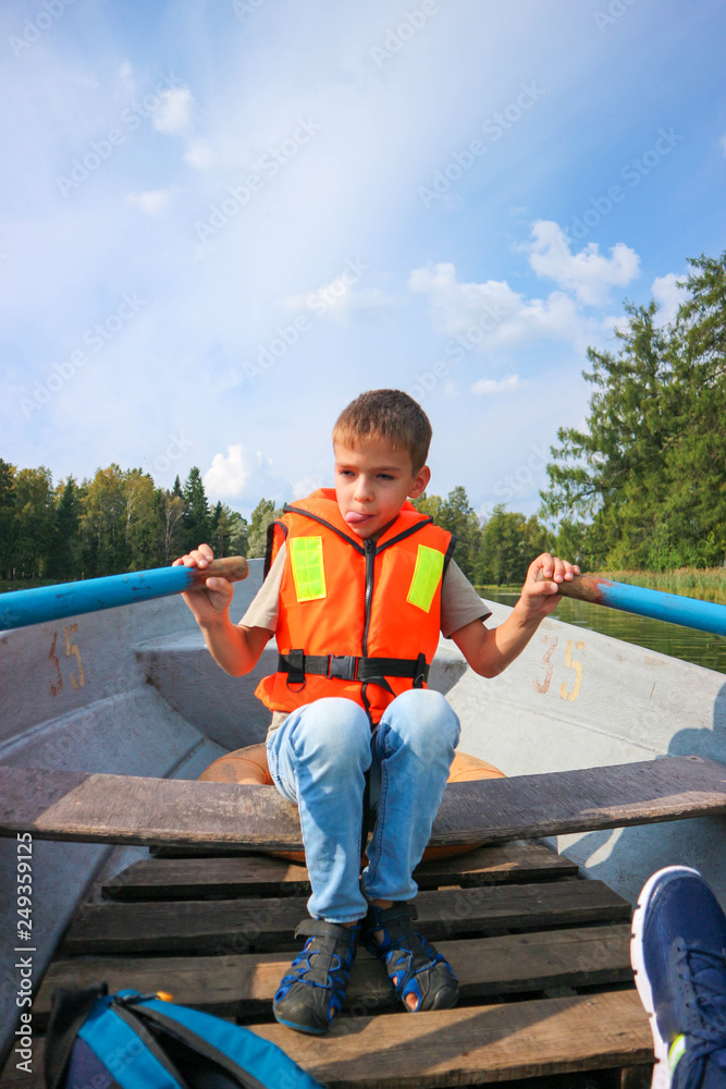 Young boy paddles in a boat in a life jacket, Gatchina park, Russia Young boy paddles in a boat in a life jacket, Gatchina park, Russia