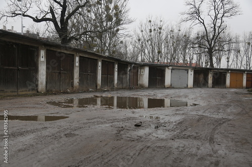 Old, neglected, ruined garages. Muddy, holey, uneven road with puddles. Winter, autumn landscape in the city. Wrocław, Wroclaw, Breslau. Lower Silesia, Dolny Śląsk. Polska, Poland, Polen photo