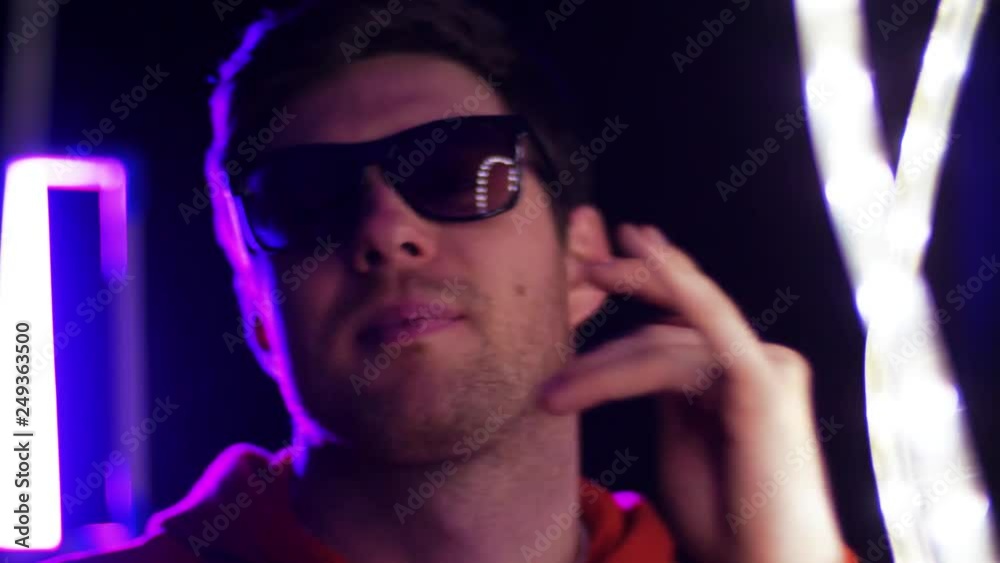 leisure, clubbing and nightlife concept - portrait of smiling young man in sunglasses dancing over ultra violet neon lights in dark room of night club leisure, clubbing and nightlife concept - portrait of smiling young man in sunglasses dancing over ultra violet neon lights in dark room of night club